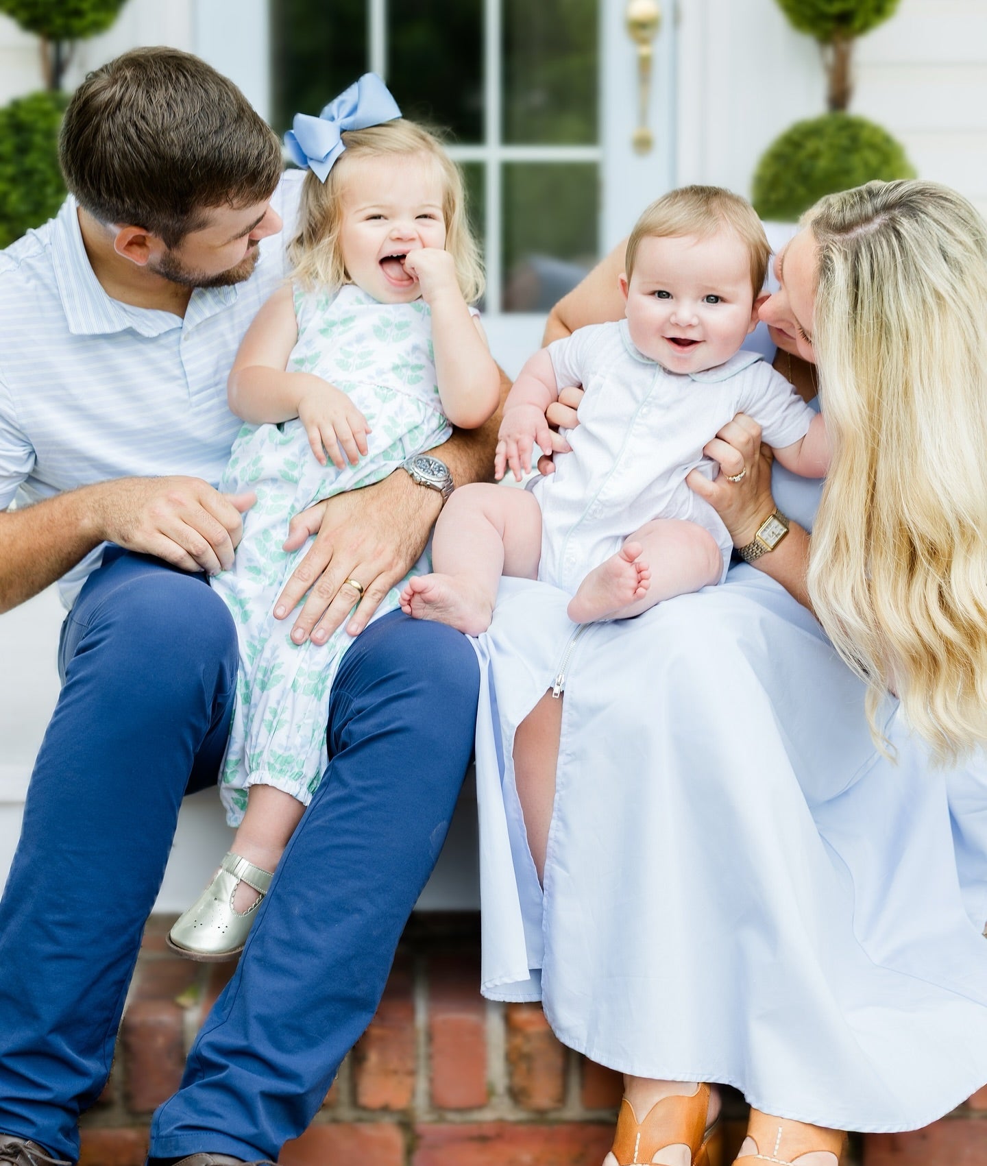 Family of four sitting together on a step outdoors